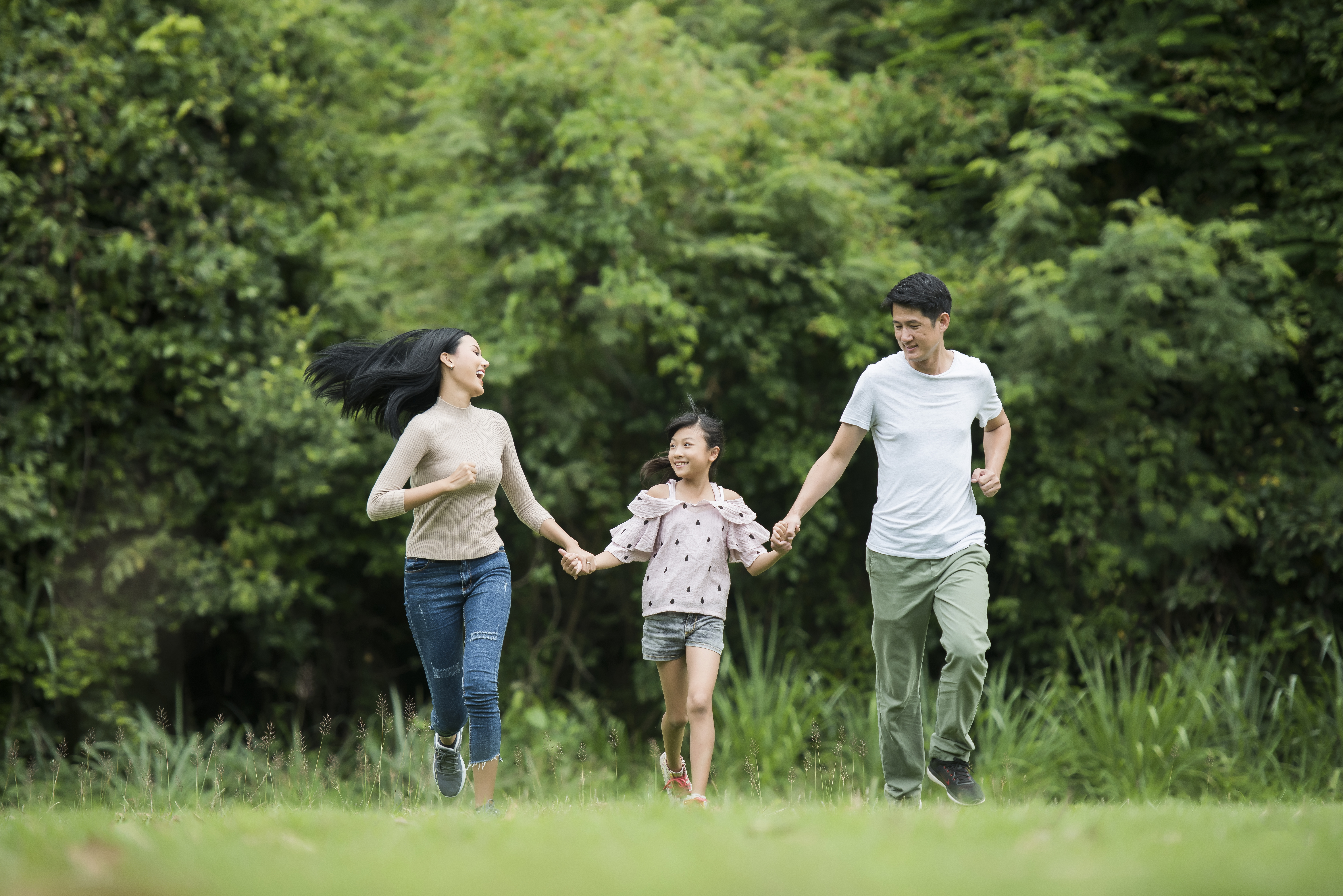 Happy family is having fun Mother, father and daughter are running in park.