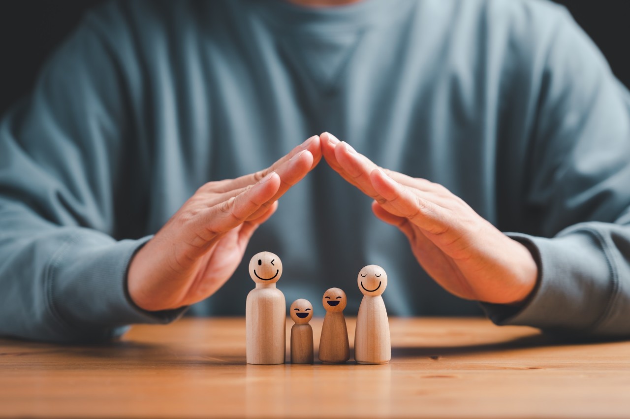 man with protective on family wooden model gesture and family, life, health and house insurance icons. Insurance concept, Family life insurance and policy concepts.